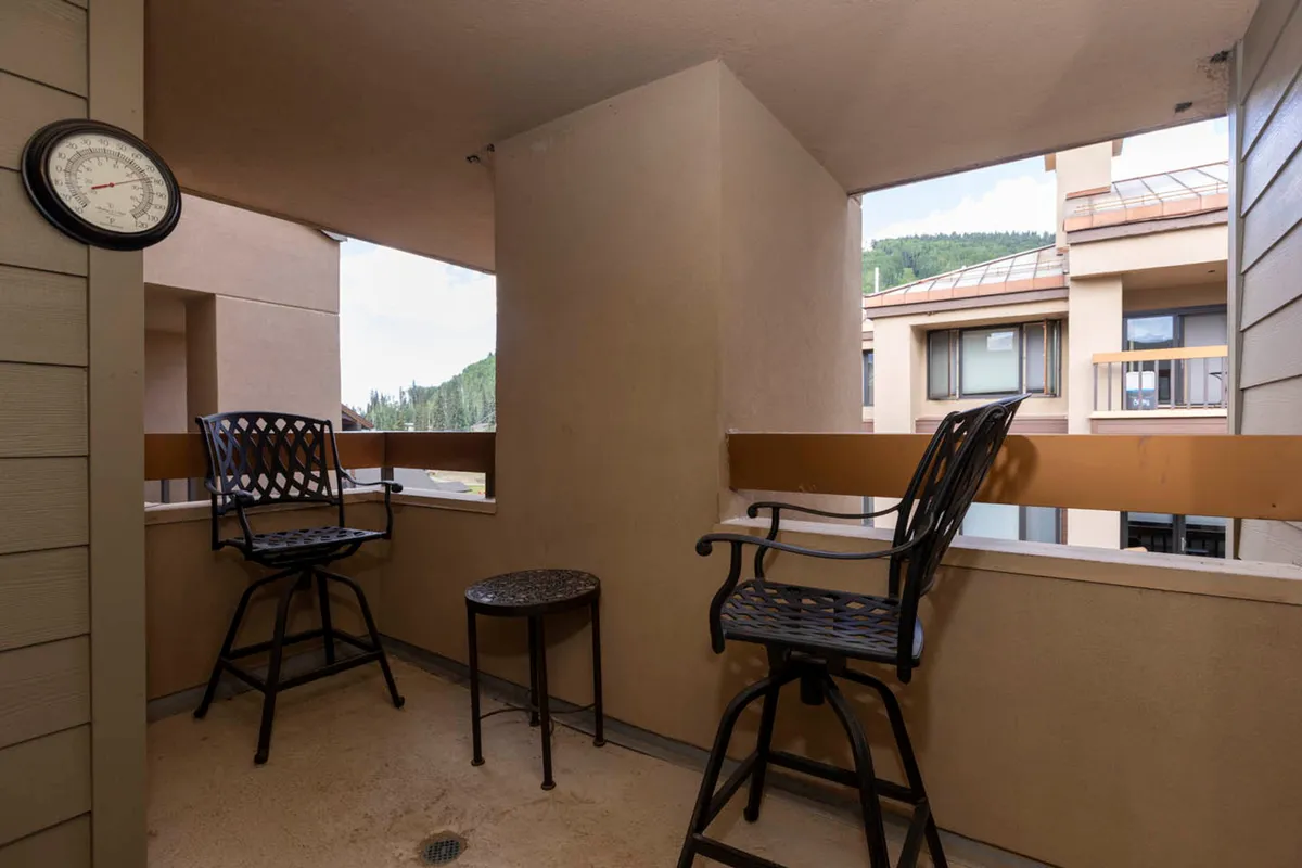 An inviting outdoor space with two high-top bar stools and a small round table, set against the backdrop of distant hills. The ambiance suggests a relaxing spot for couples to sip drinks at sunset or enjoy stargazing together, fostering intimacy and connection with the surrounding mountain scenery.